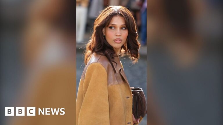 Nara Smith has brown hair ad is wearing a tan leather jacket.