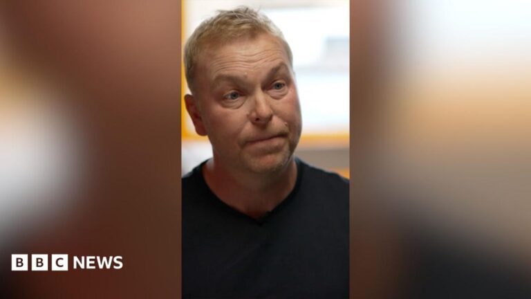 A blonde man, Sir Chris Hoy, in a black t shirt.