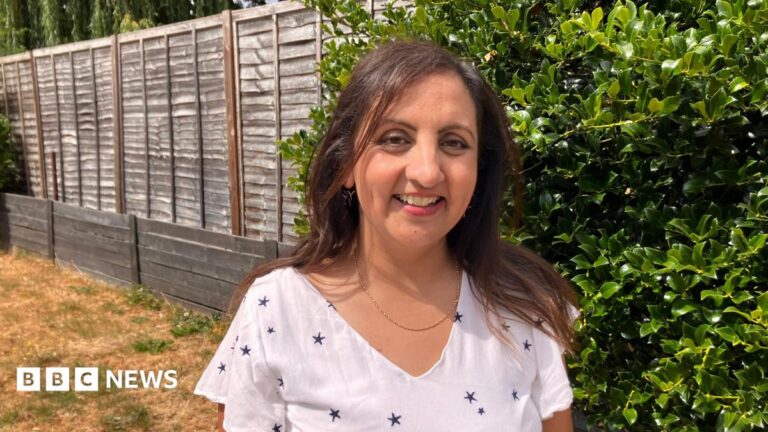 Oxford vaccine trial hope for hereditary cancer risk families Bep Sandhu standing in a garden she is smiling at the camera. She wears a white top with small dark stars on and a thin gold necklace.